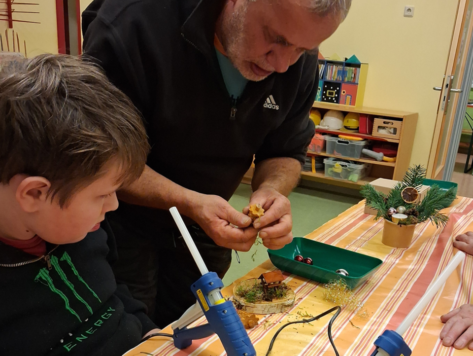 Ein Vater gestaltet mit seinem Sohn ein Advenstgesteck.