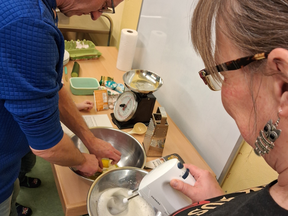 Zwei Erwachsene stellen den Teig für die Kräuterwaffeln her.