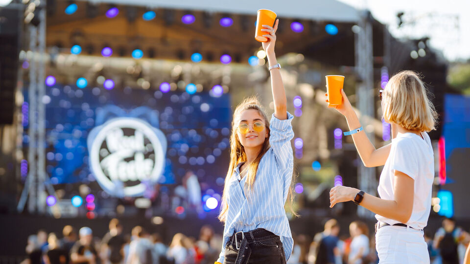Two young woman drinking beer and having fun at Beach party together. Music festival. Summer holiday, vacation concept.