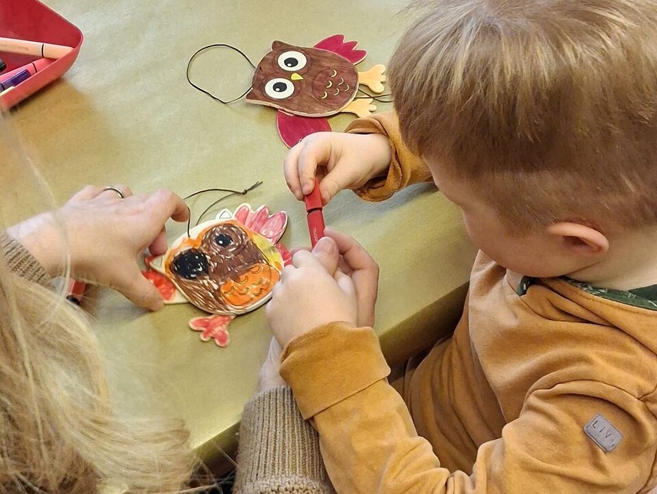 Ein Junge malt eine Holzeule an.