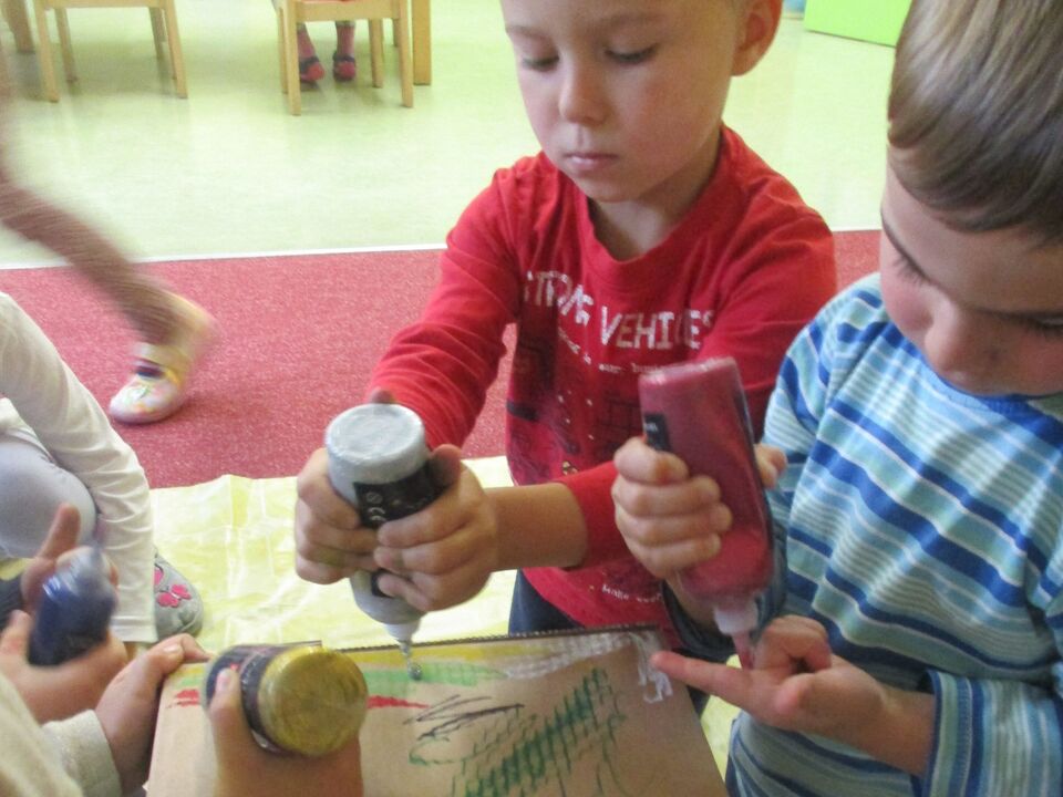 Kinder bemalen mit Farbe einen Geschenkkarton.