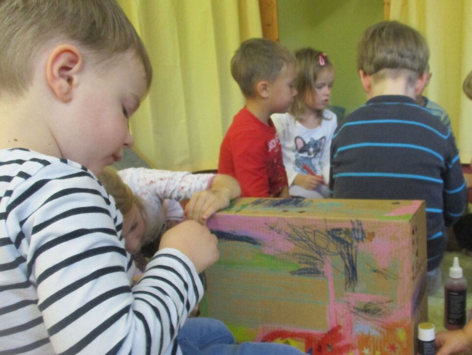 Ein Kind bemalt einen Geschenkkarton.